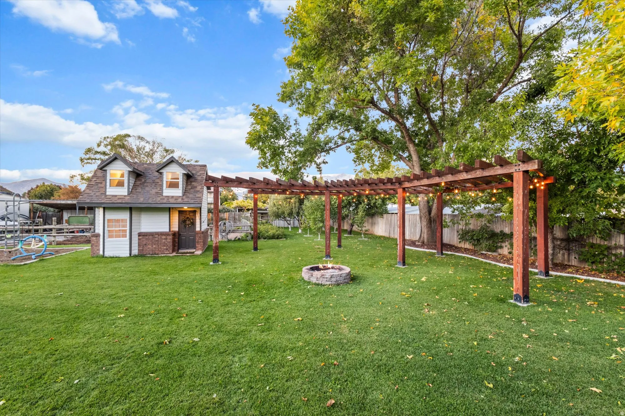 Fenced backyard with a pergola, an outdoor fire pit and playhouse