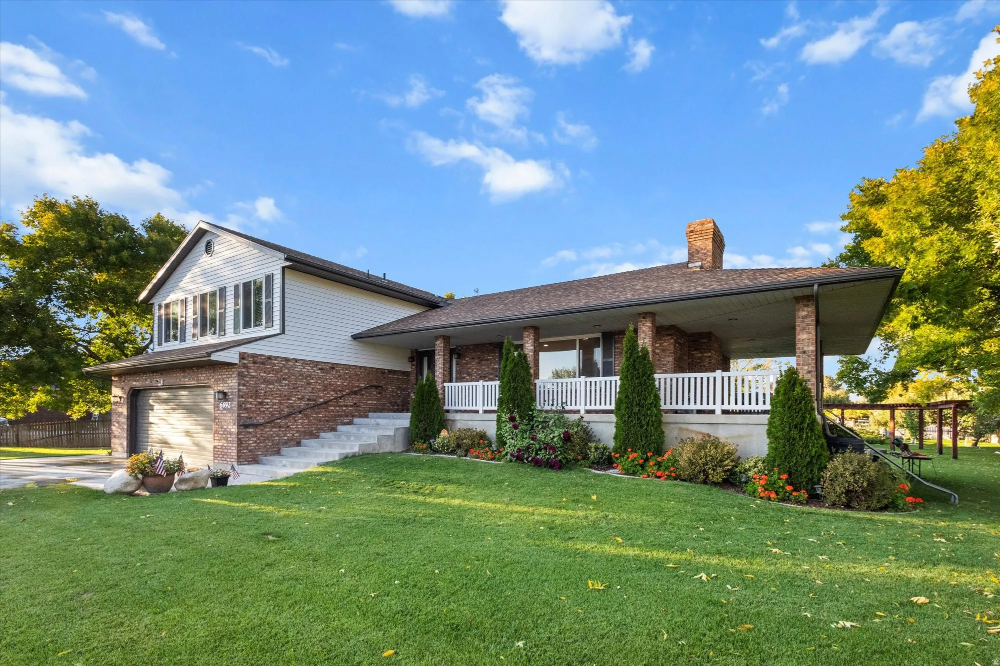 Tri-level home featuring brick siding, a garage, a front lawn, a chimney, and a porch