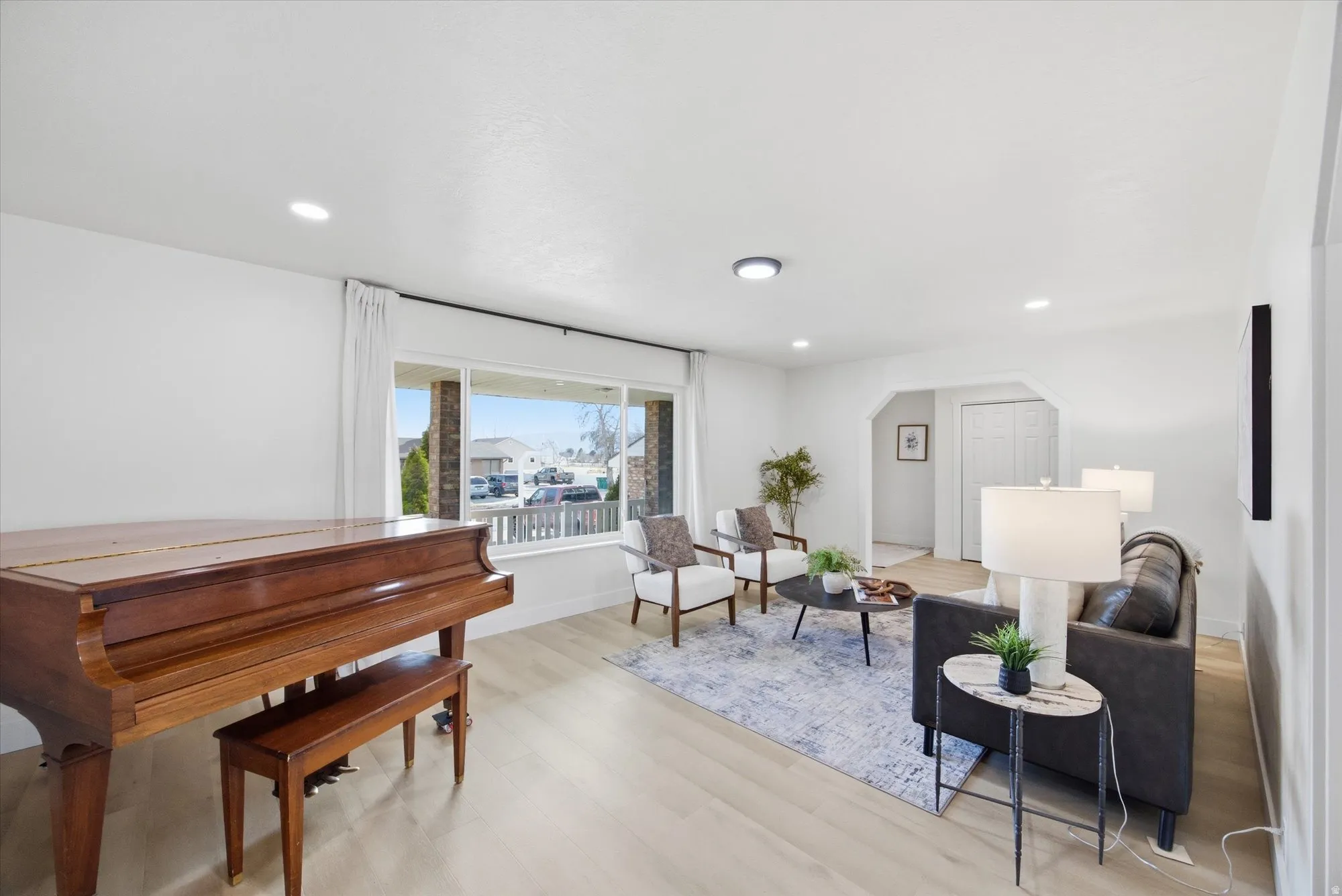 Living area with arched walkways, light LVP flooring, and recessed lighting