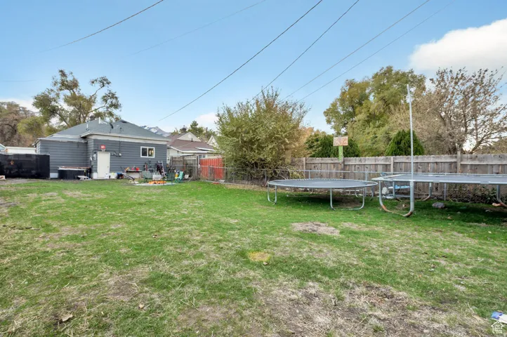 Fenced backyard featuring a trampoline