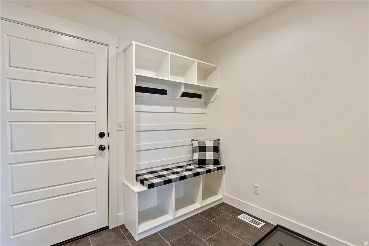 Mudroom featuring baseboards and dark tile patterned floors