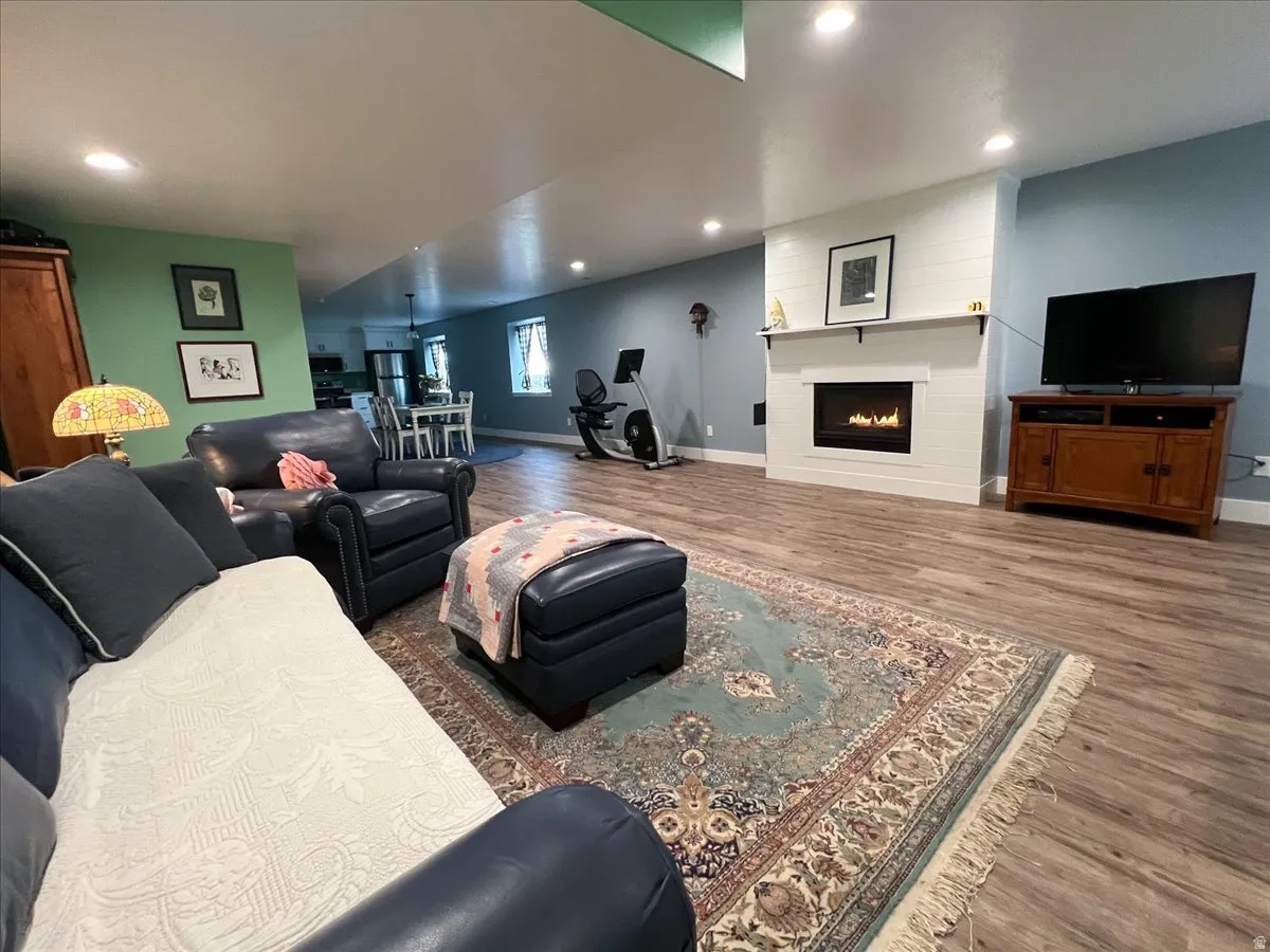 Living area with wood finished floors, a large fireplace, and recessed lighting