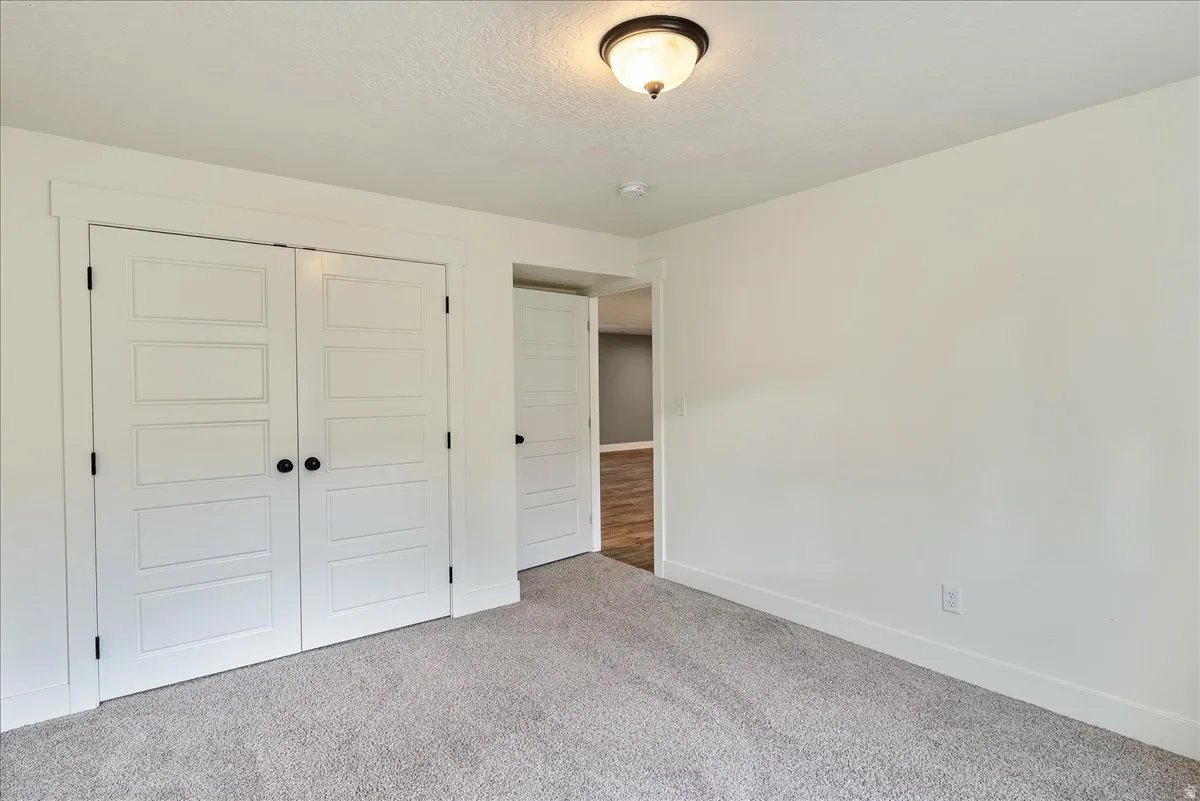Unfurnished bedroom featuring a closet, carpet, and a textured ceiling