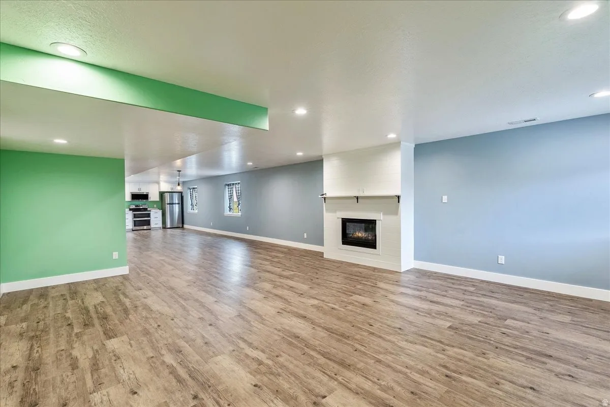 Unfurnished living room featuring a large fireplace, recessed lighting, and light wood finished floors