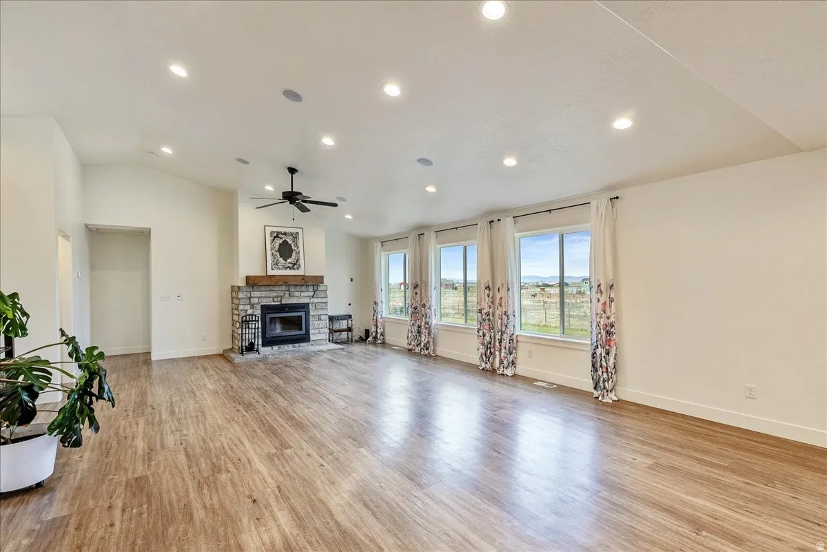 Unfurnished living room featuring lofted ceiling, light wood-type flooring, recessed lighting, a ceiling fan, and a fireplace
