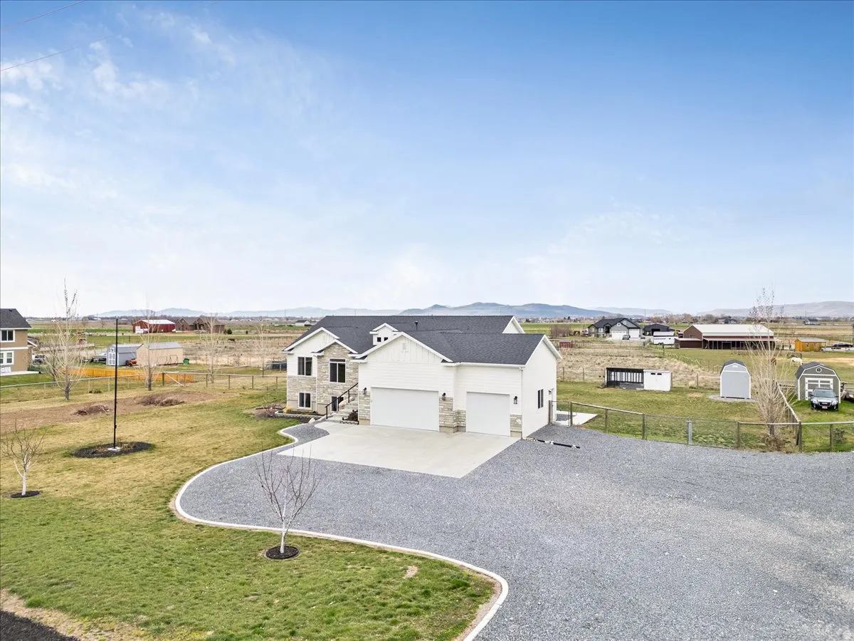 Modern inspired farmhouse with stone siding, gravel driveway, an attached garage, a mountain view, and board and batten siding