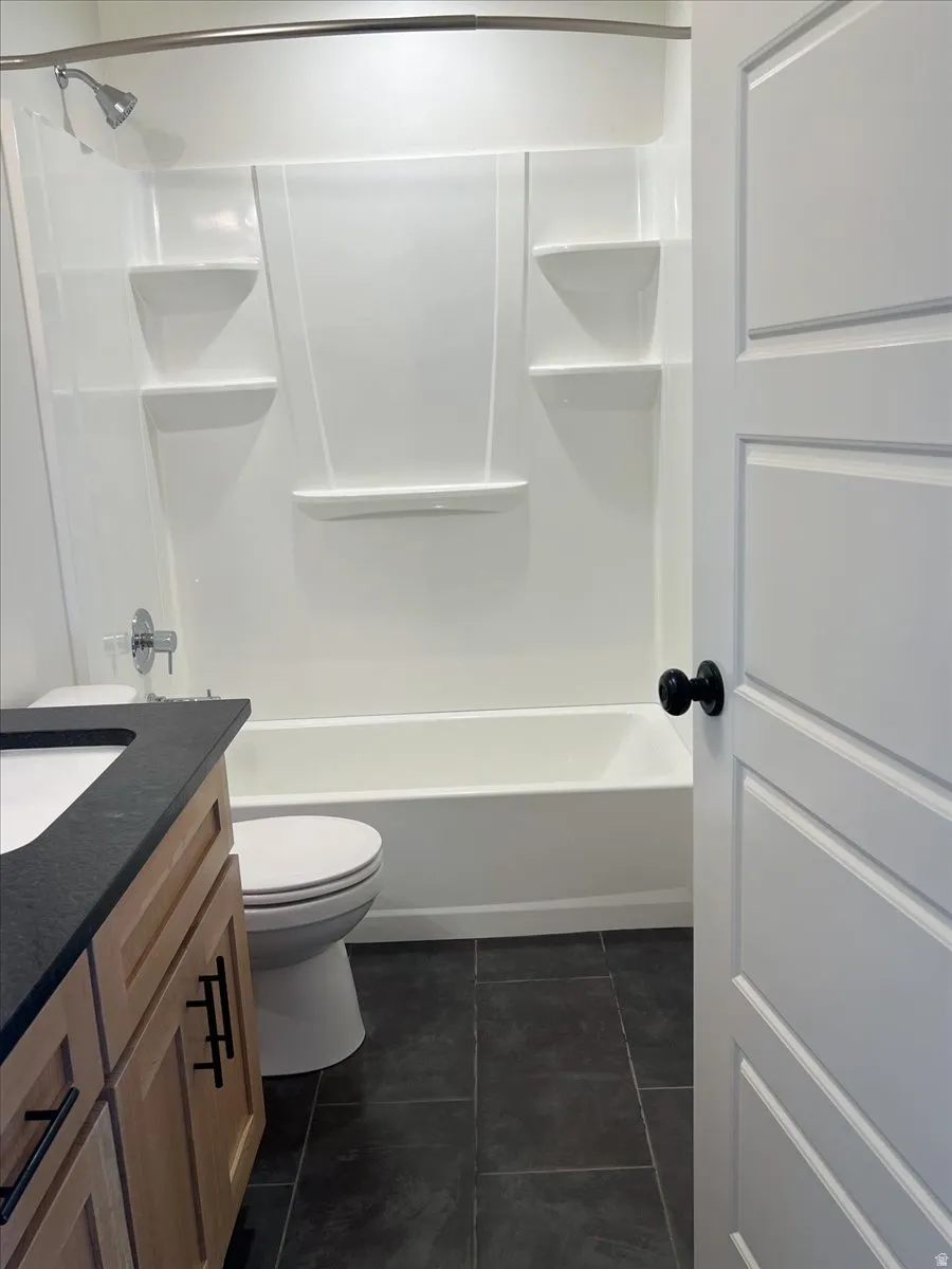Full bath with vanity, shower / bath combination, and dark tile patterned floors