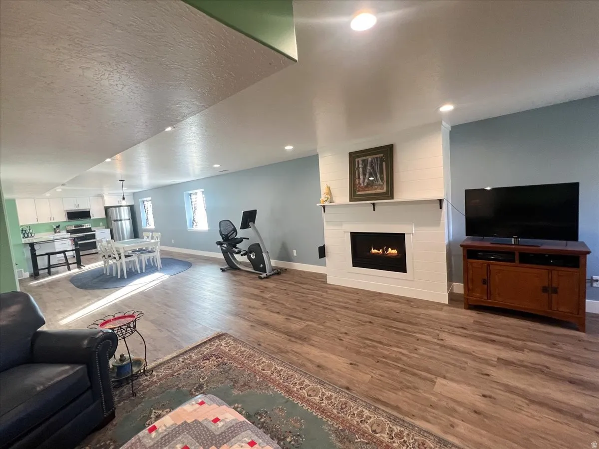 Living room featuring dark wood-type flooring, a lit fireplace, and a textured ceiling