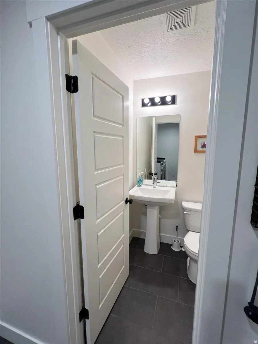 Half bathroom featuring a textured ceiling and dark tile patterned floors
