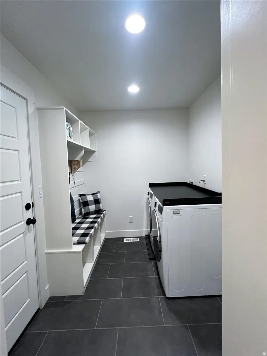 Laundry area featuring separate washer and dryer, dark tile patterned flooring, and recessed lighting