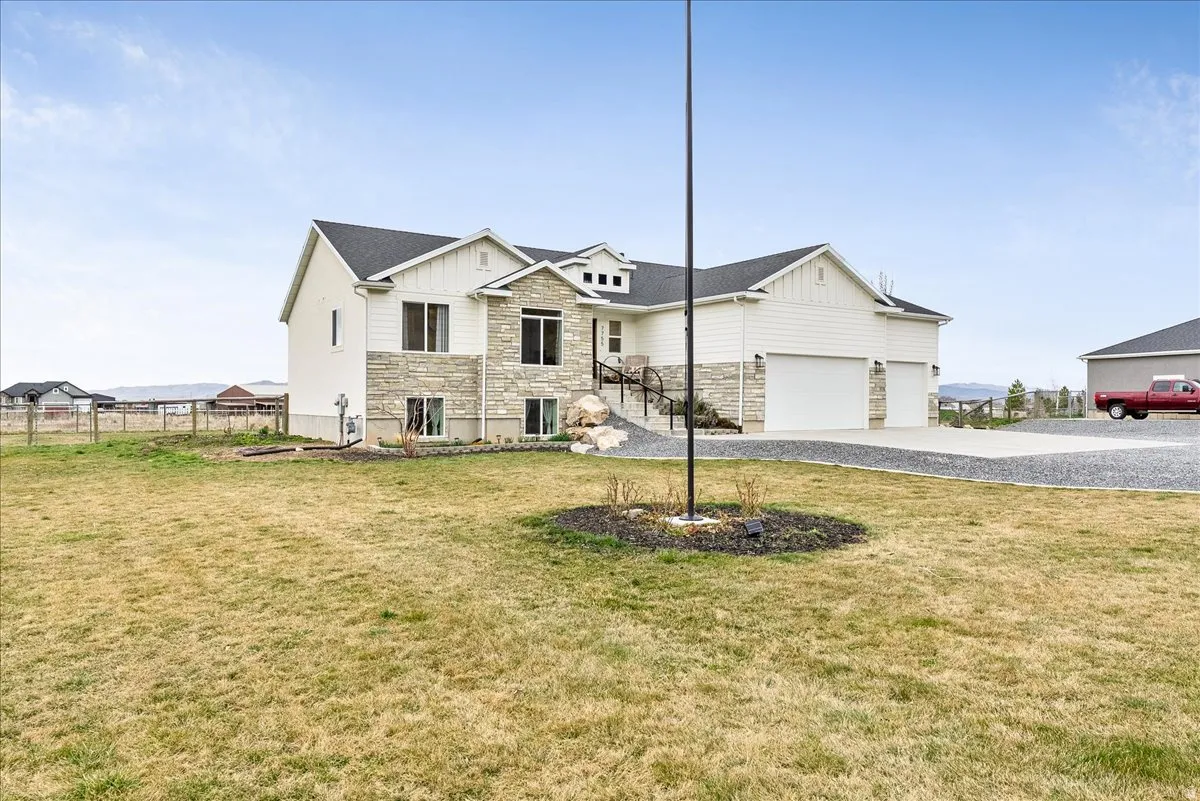 View of front of house featuring stone siding, board and batten siding, driveway, a garage, and roof with shingles
