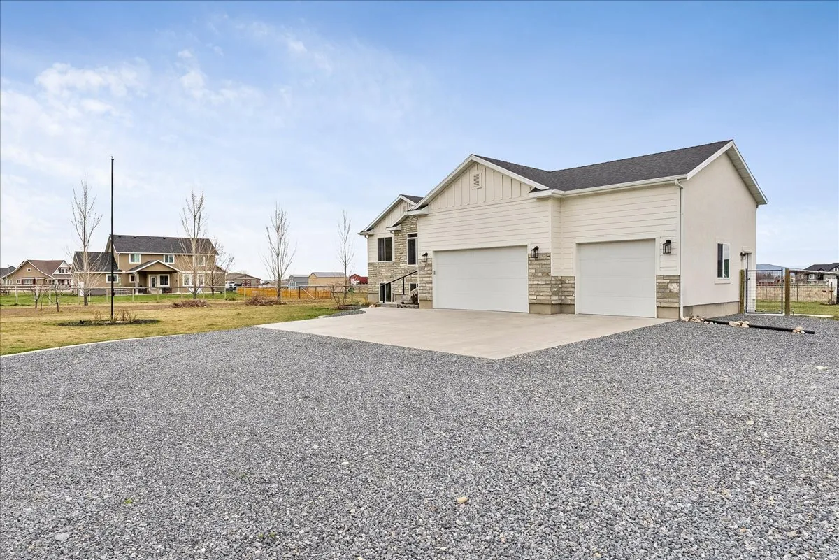View of side of home with concrete driveway, an attached garage, stone siding, board and batten siding, and a residential view