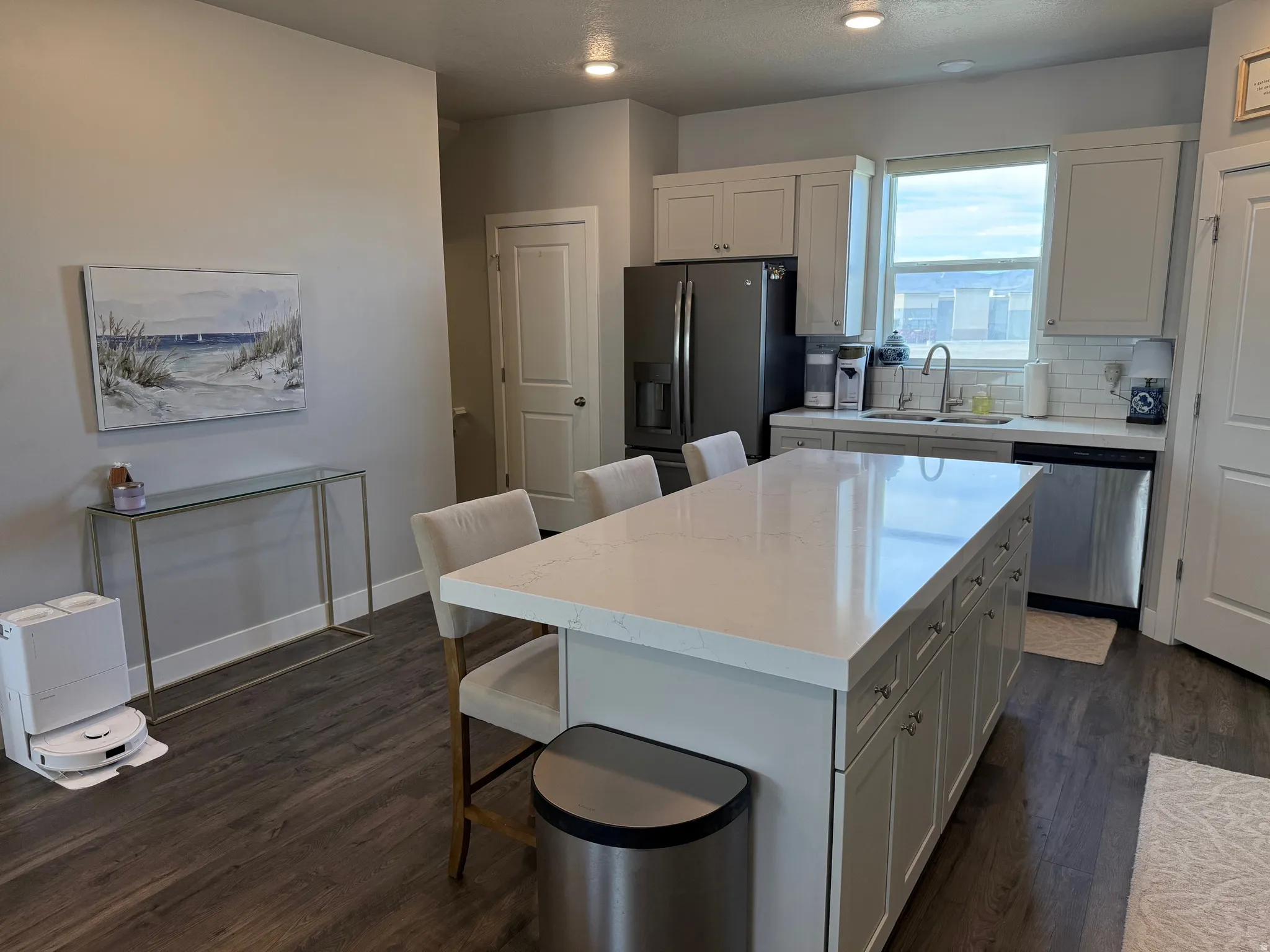 Kitchen with a kitchen breakfast bar, white cabinetry, decorative backsplash, stainless steel appliances, and dark wood-style floors, stainless appliances