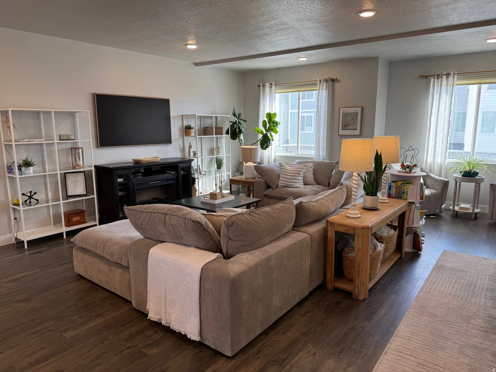 Living area with a textured ceiling, dark wood-style floors, a fireplace, and recessed lighting
