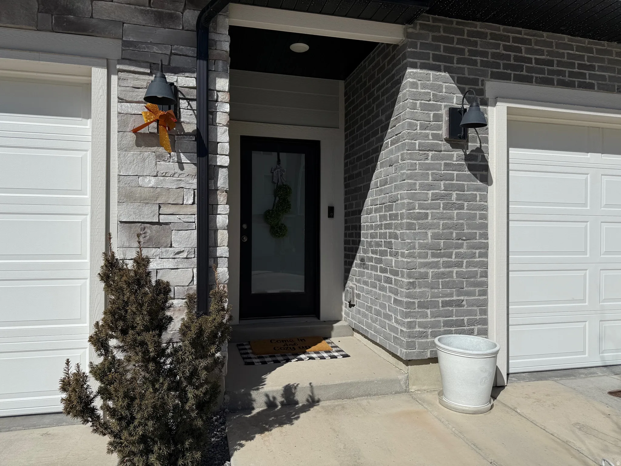 Property entrance with brick siding, a porch, and a garage
