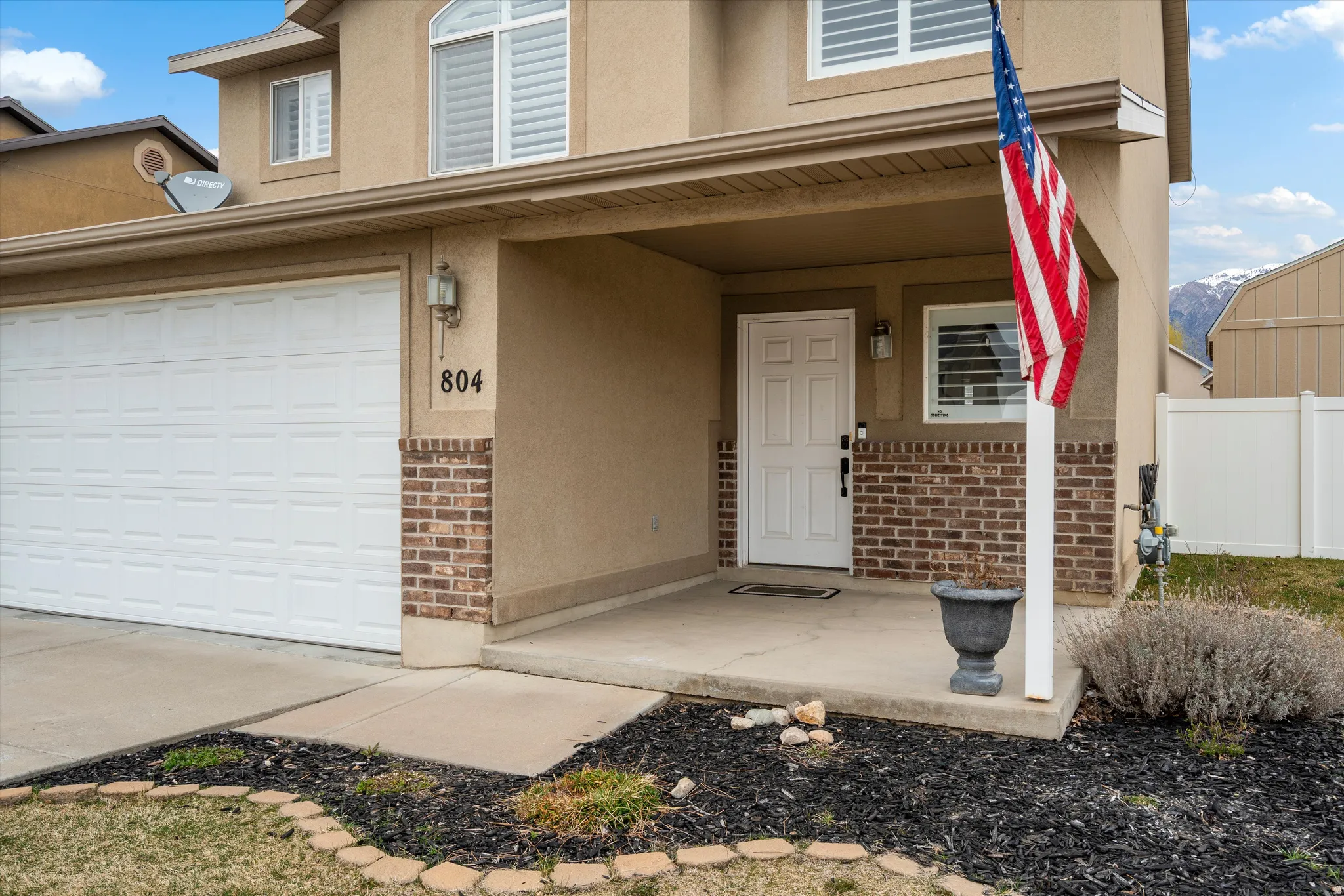 View of front of house featuring covered porch, brick siding, stucco siding, and a garage