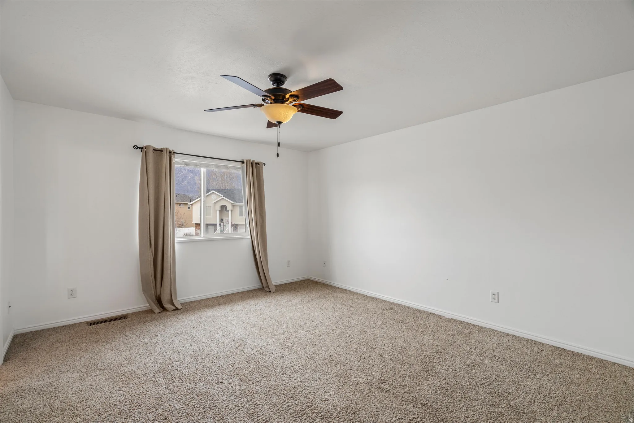 Carpeted spare room with a ceiling fan and baseboards