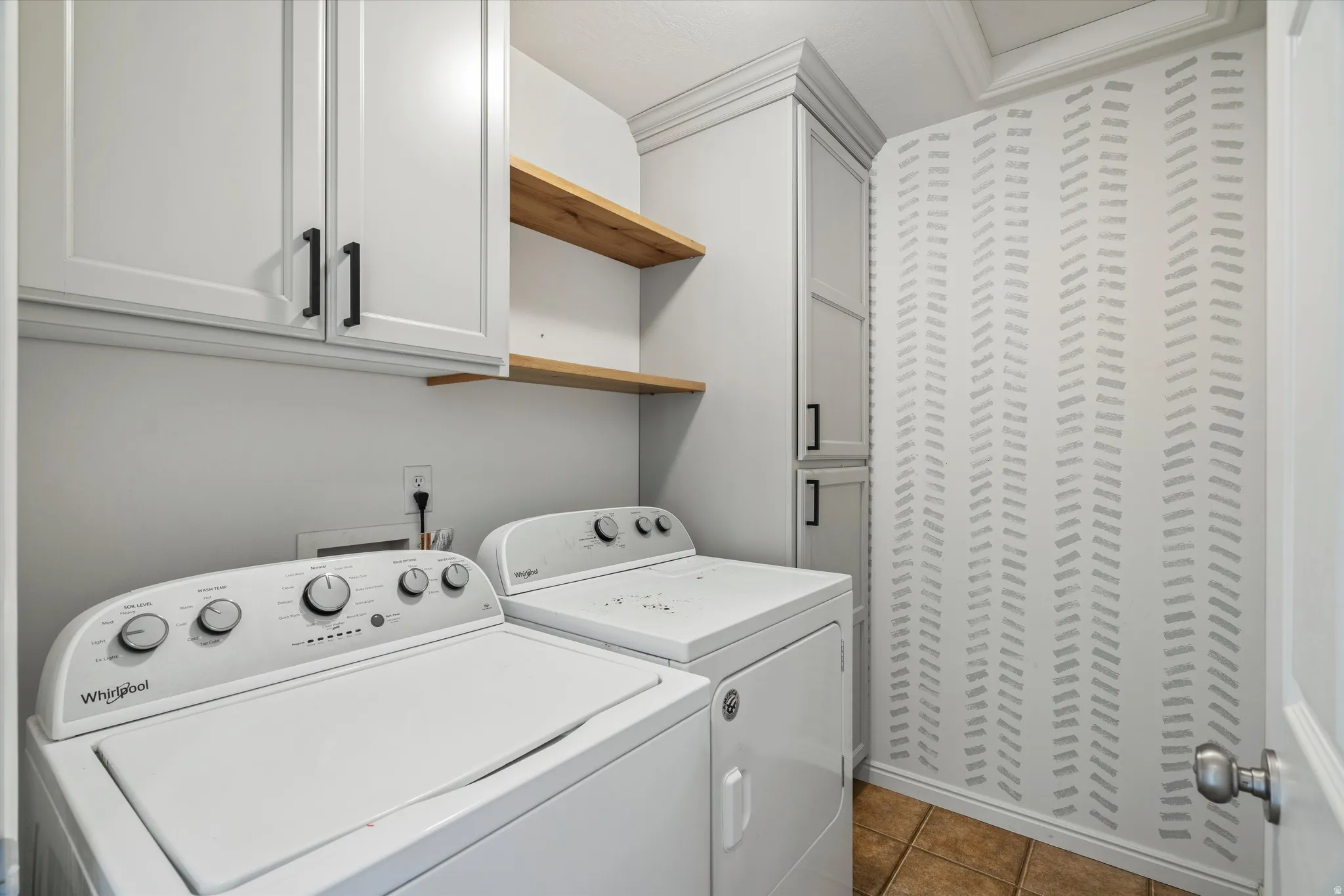 Laundry area with cabinet space, dark tile patterned floors, and separate washer and dryer