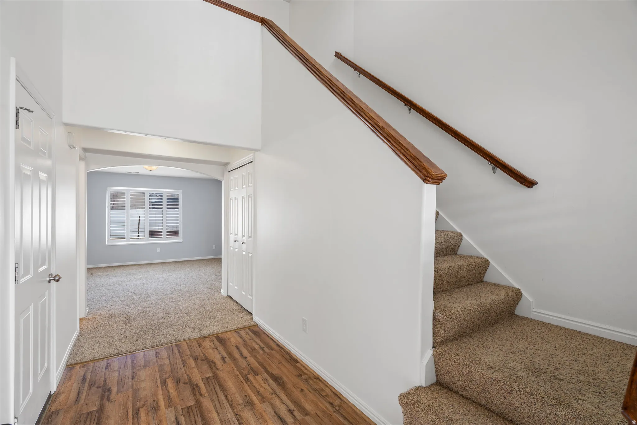 Stairway with a high ceiling, arched walkways, wood finished floors, and carpet