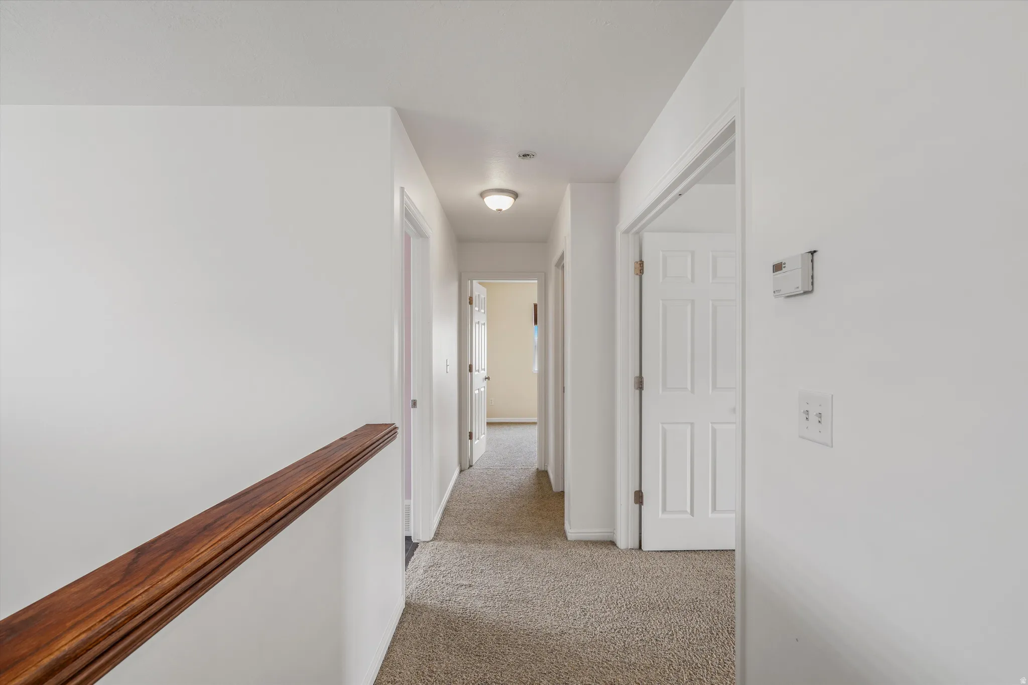 Corridor featuring light colored carpet and an upstairs landing