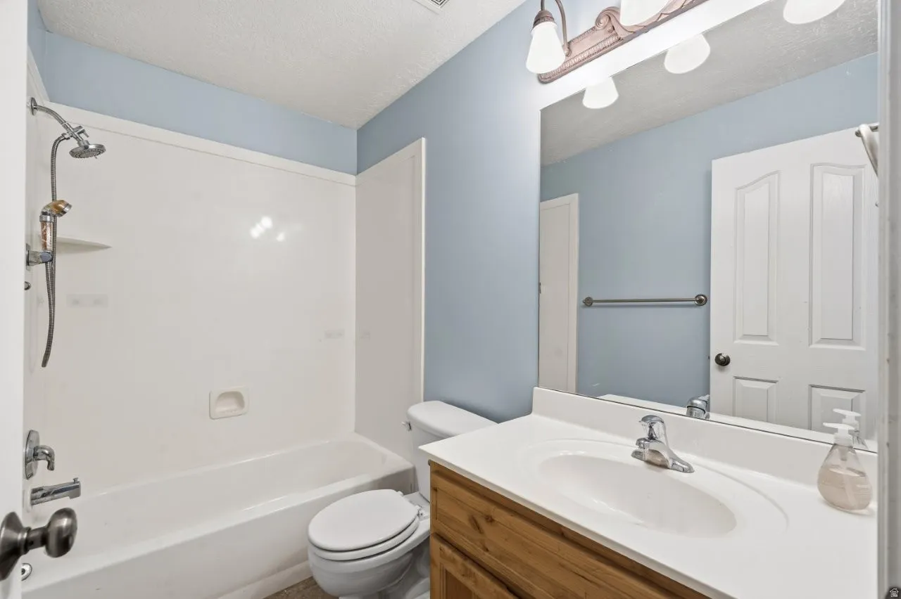 Bathroom featuring a textured ceiling, vanity, and shower / bathtub combination