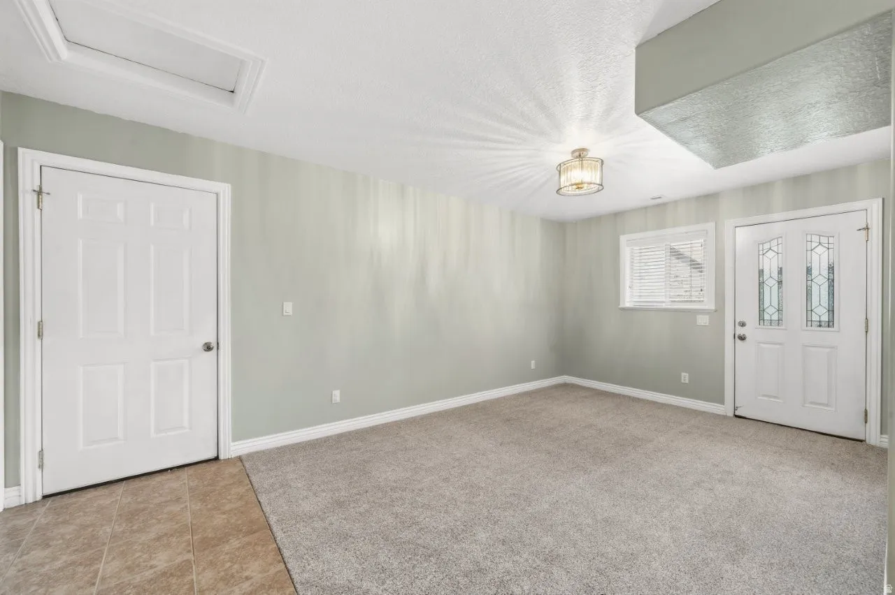 Entryway featuring light colored carpet, a textured ceiling, and light tile patterned floors