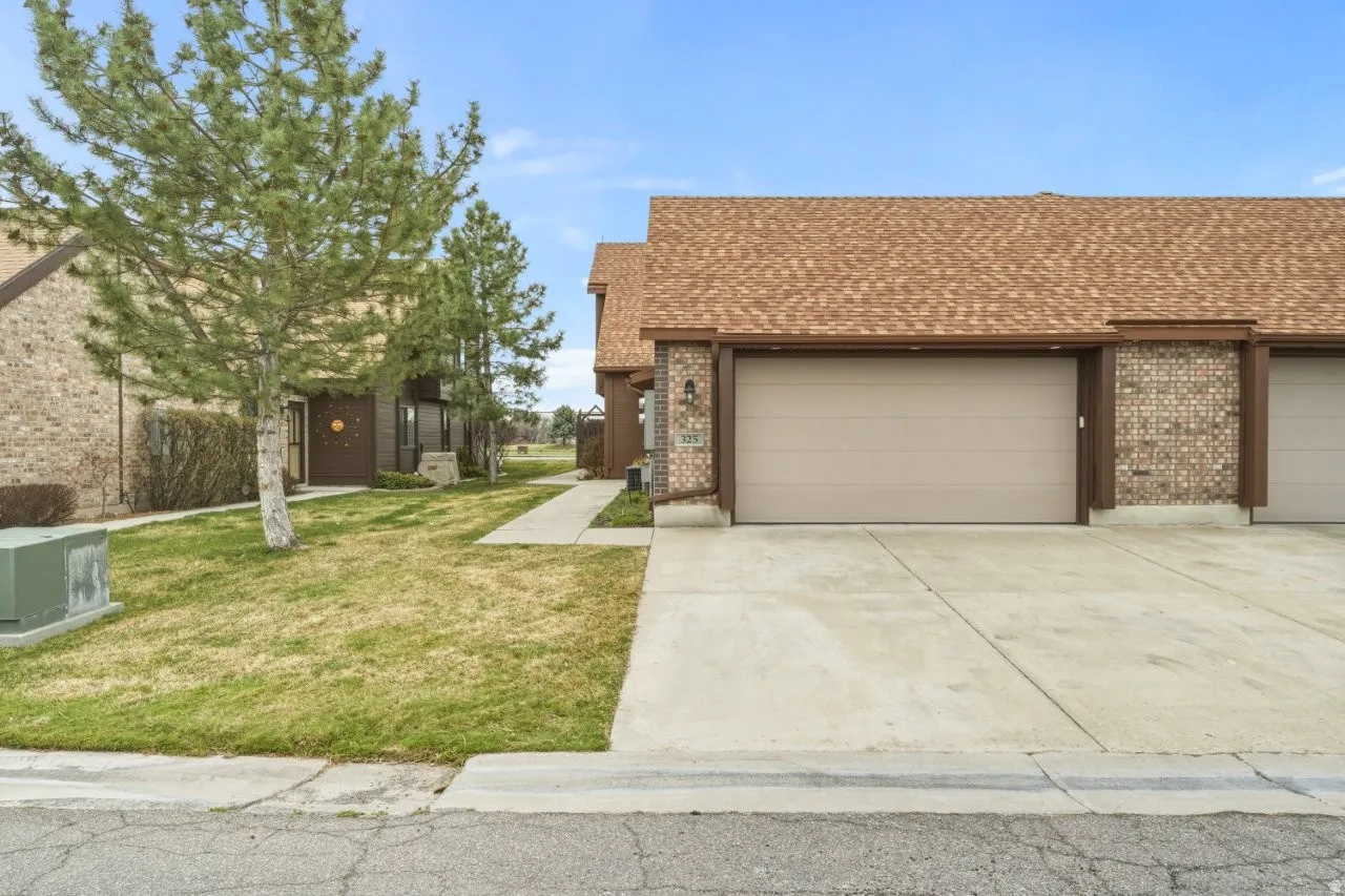 View of front of home featuring a shingled roof, an attached garage, driveway, and brick siding
