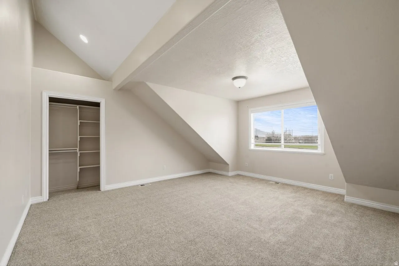 Bonus room with light carpet and vaulted ceiling