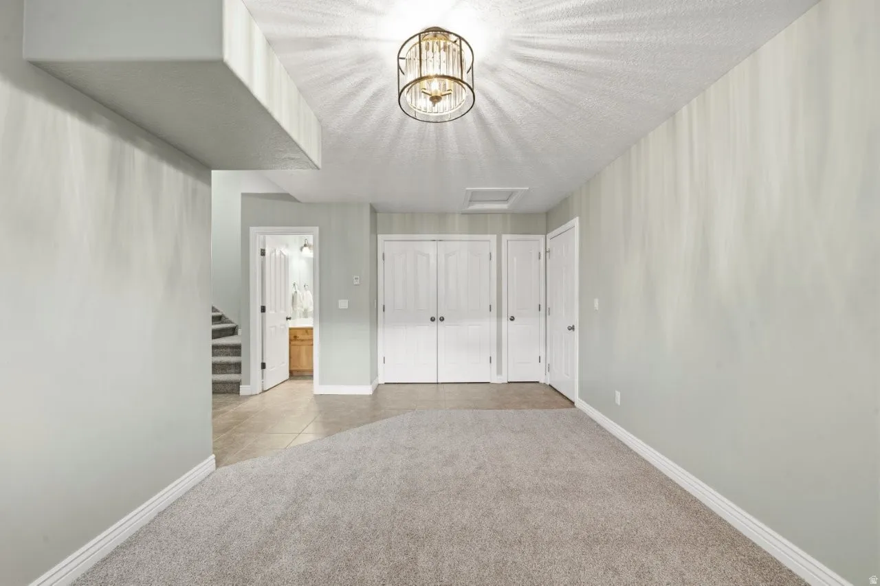 Unfurnished bedroom with light carpet, a closet, ensuite bath, and a chandelier