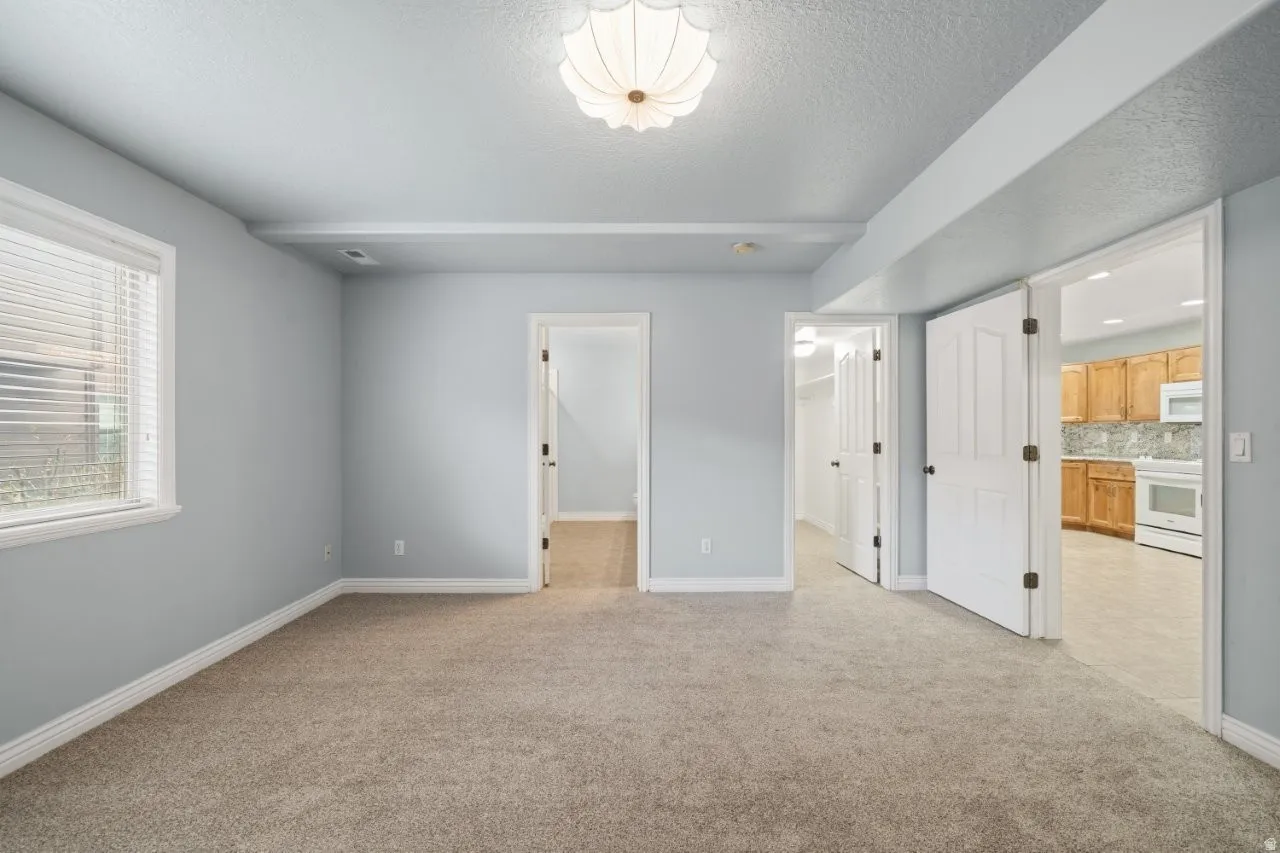 Unfurnished bedroom featuring light carpet, a spacious closet, connected bathroom, and a textured ceiling
