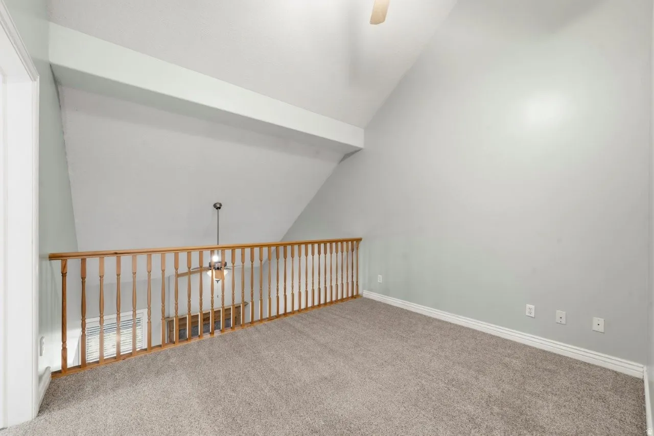 Spare room featuring ceiling fan, vaulted ceiling, and carpet flooring