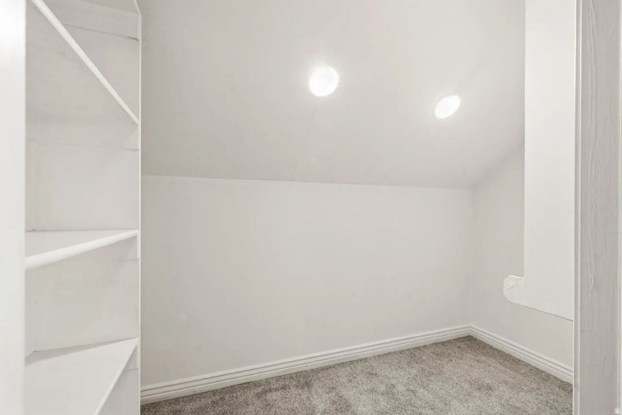 Bonus room with light colored carpet and vaulted ceiling