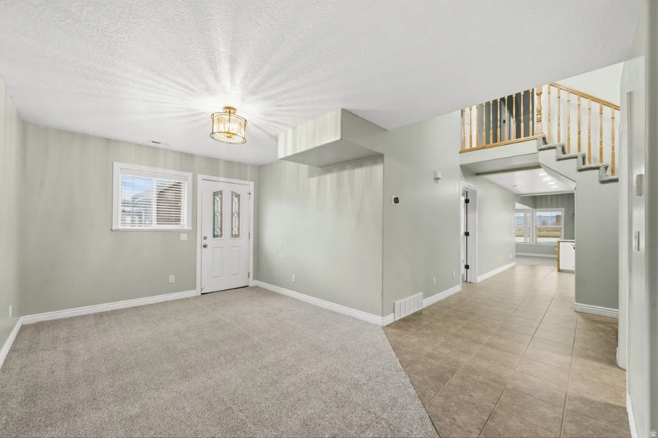 Foyer entrance featuring a textured ceiling and light colored carpet