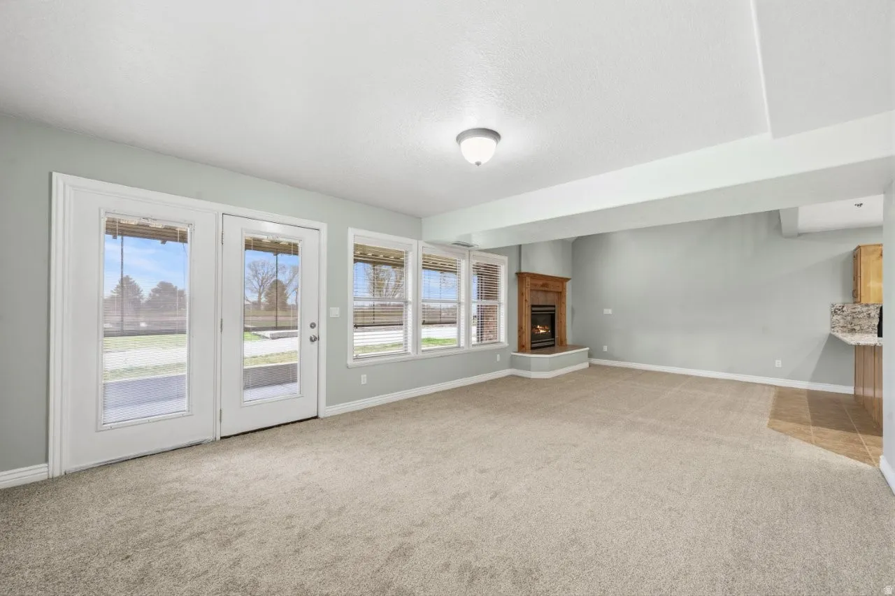 Unfurnished living room with light colored carpet, healthy amount of natural light, a warm lit fireplace, and a textured ceiling