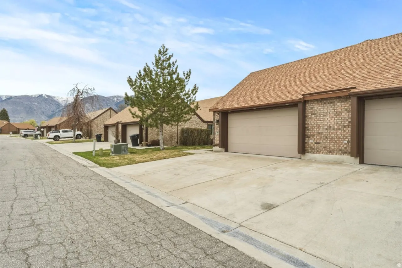 View of front of home with roof with shingles, a residential view, brick siding, a mountain view, and driveway