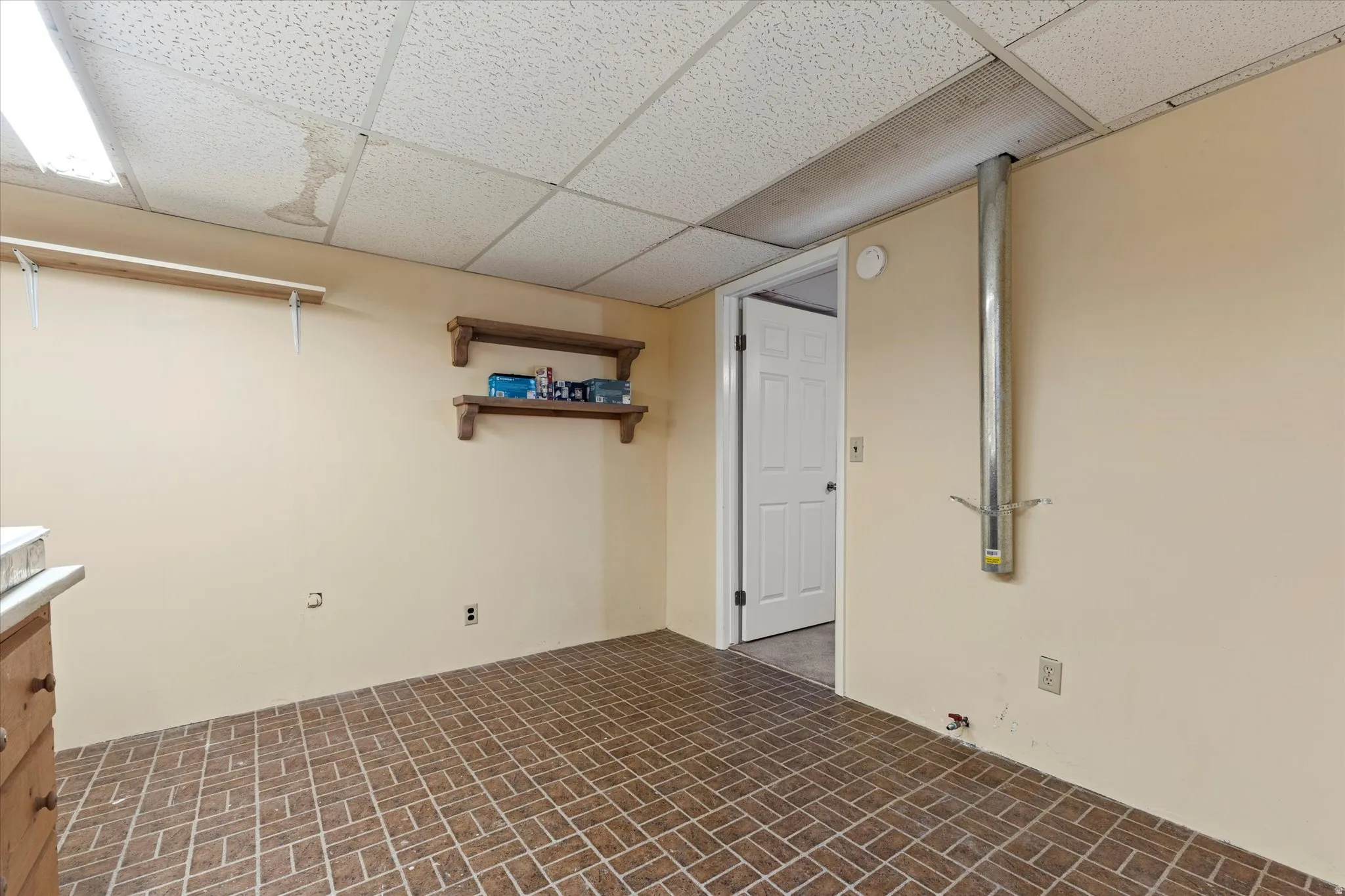 Dedicated laundry and utility space with built-in workbench, cabinetry, and pegboard wall for organized storage and projects. Durable flooring, overhead lighting, and additional shelving provide a functional area for laundry, hobbies, or workspace needs.