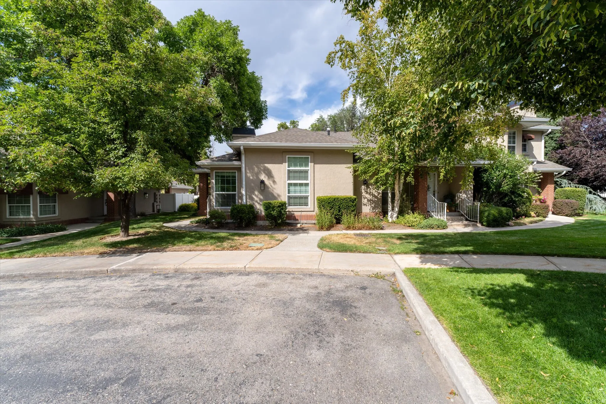 Well-maintained exterior with mature trees, manicured landscaping, and a welcoming walkway leading to the entrance.