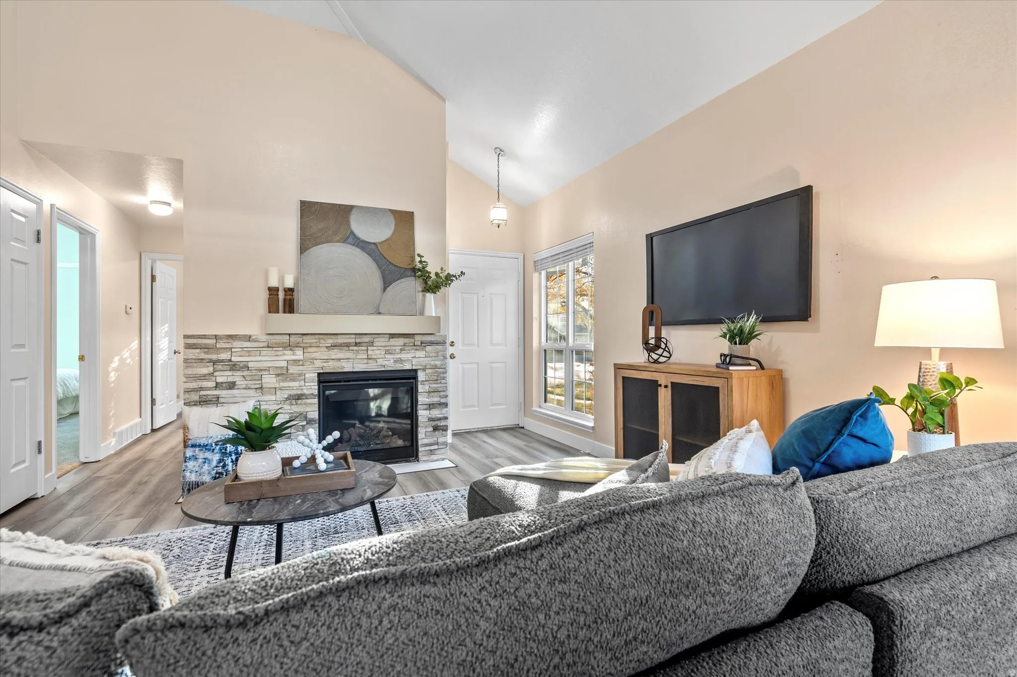 Cozy living space featuring a stone-accented fireplace as the focal point, complemented by modern flooring and a functional layout.