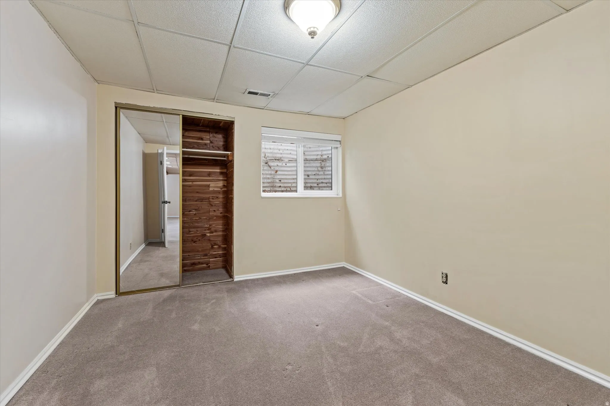 Functional bedroom with built-in cedar closet space and natural light from a window, enhancing everyday livability.