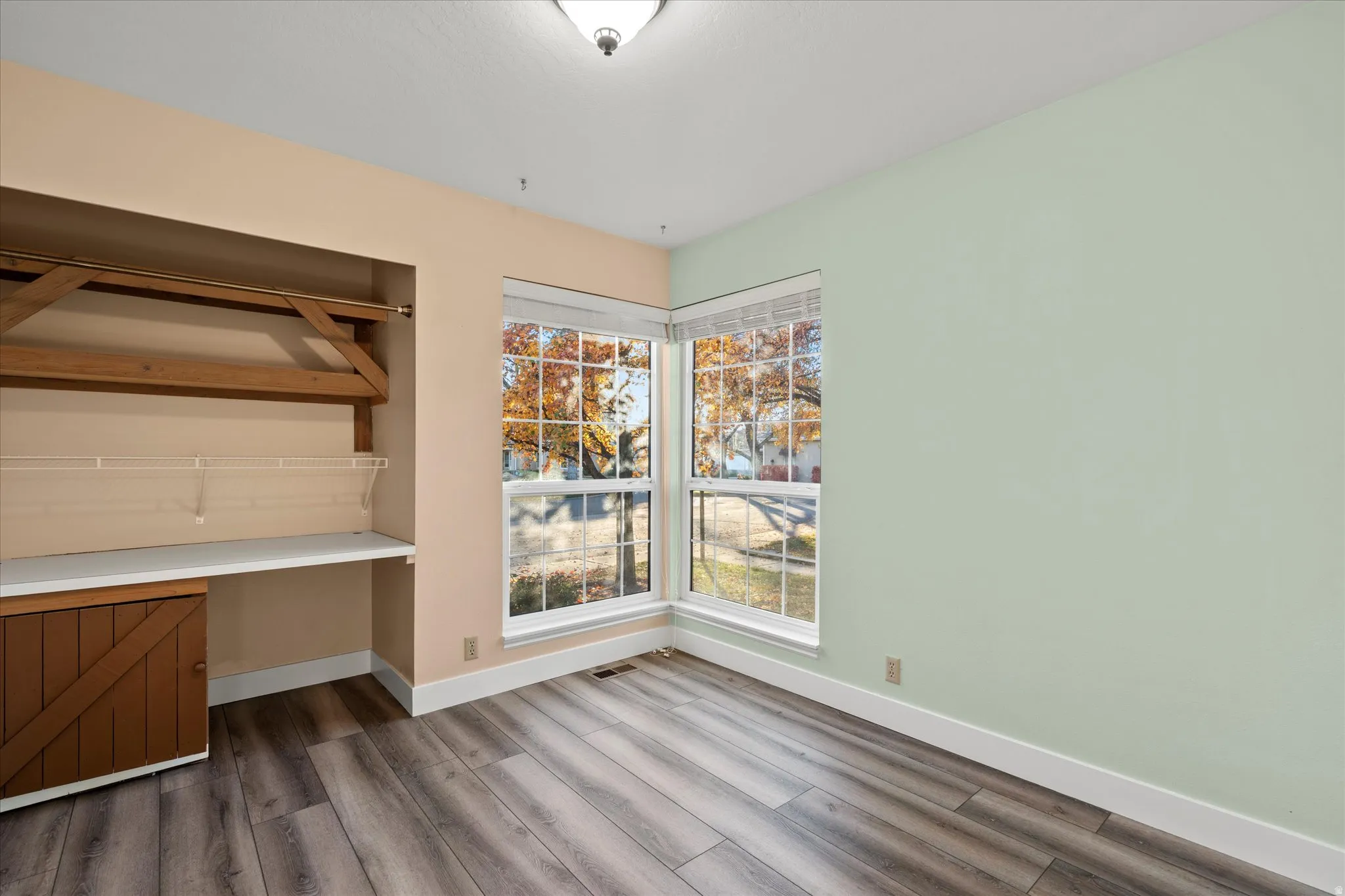 Bright room with large corner windows and built-in shelving, ideal for a bedroom, home office, or hobby space.