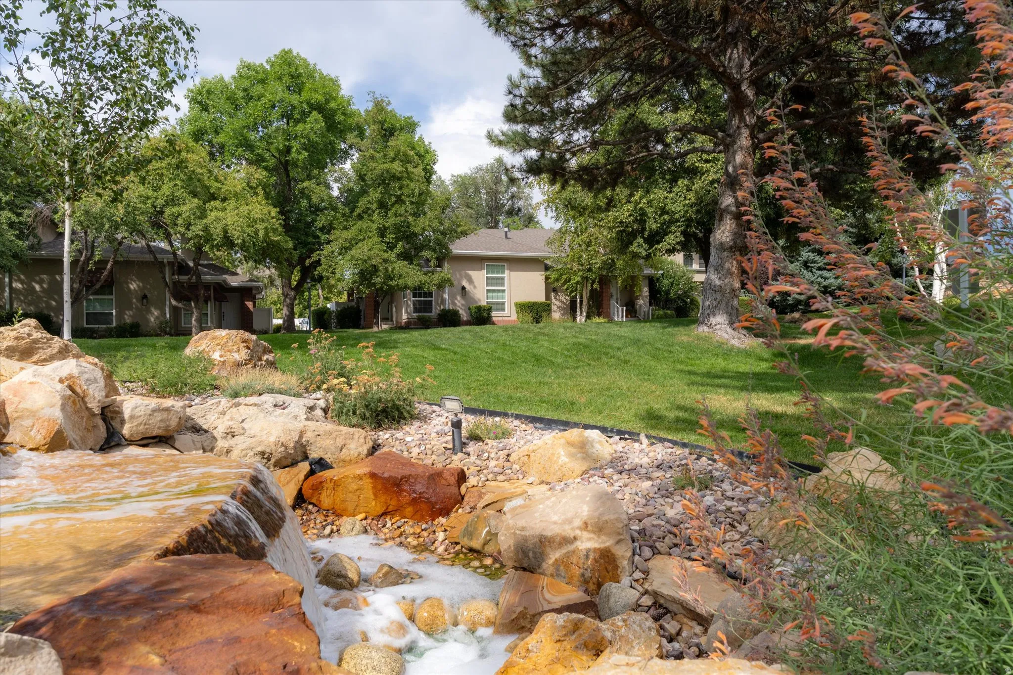 Scenic landscaped water feature with natural stone accents and flowing waterfall, creating a tranquil and inviting outdoor environment.