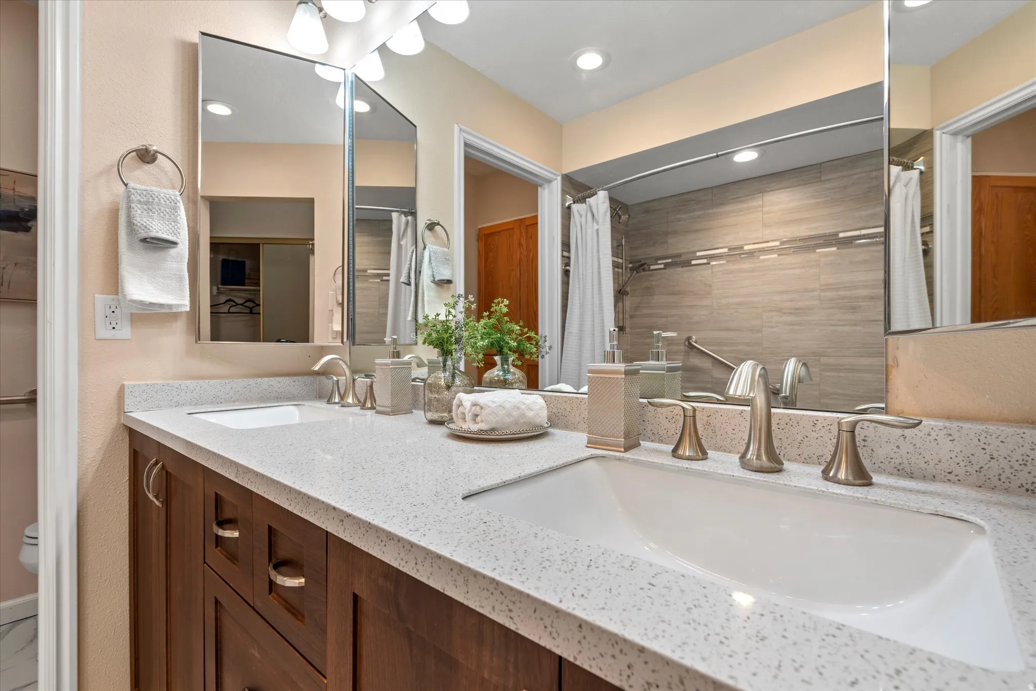 Updated bathroom featuring a dual-sink vanity with solid-surface countertops, modern fixtures, and abundant storage.