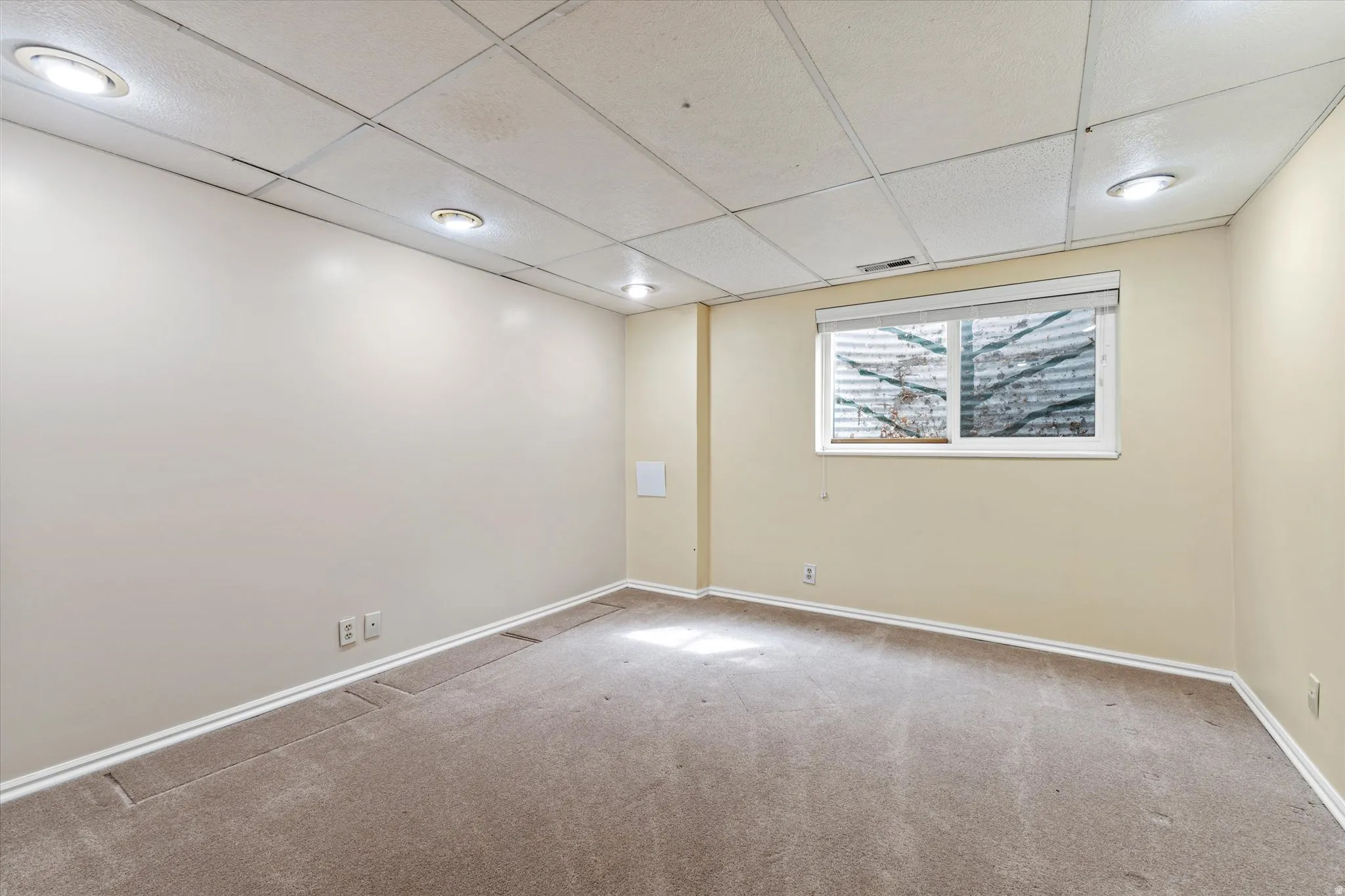 Spacious lower-level bedroom with neutral tones, soft carpeting, and recessed lighting, offering comfortable and flexible use.
