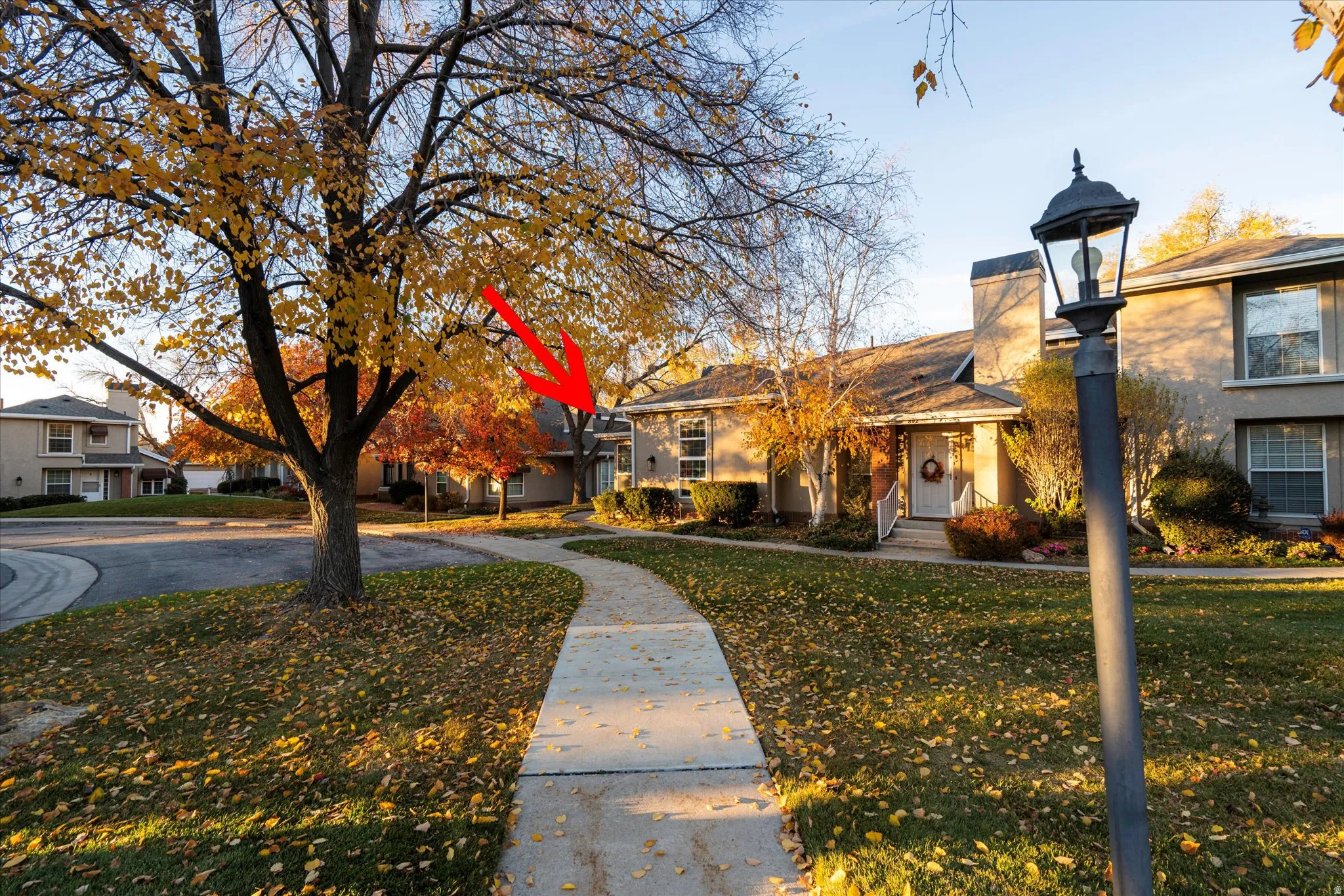 Charming exterior with tree-lined walkways and mature landscaping, highlighting the unit’s location within the community.