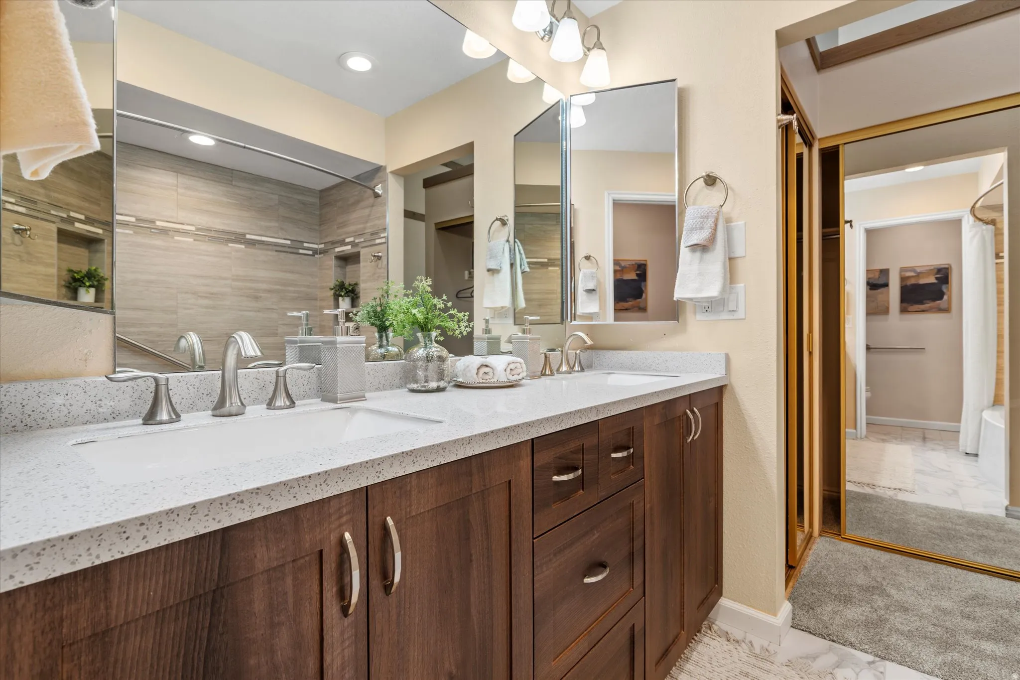 Well-designed vanity area with ample cabinetry and lighting, connected to a walk-in closet for convenient organization.