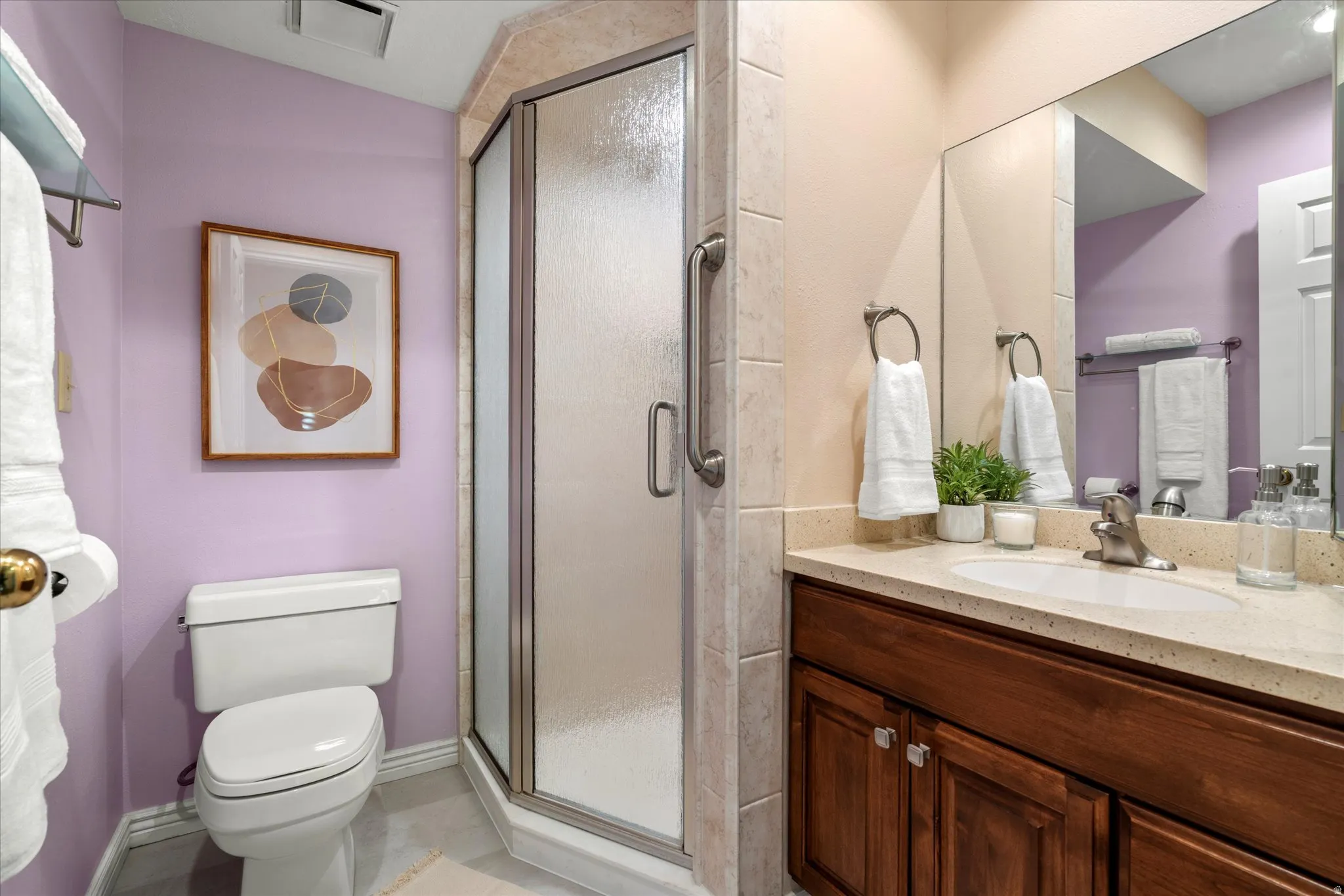 Functional bathroom with a walk-in shower, solid-surface vanity, and well-lit mirror, providing a clean and practical layout.
