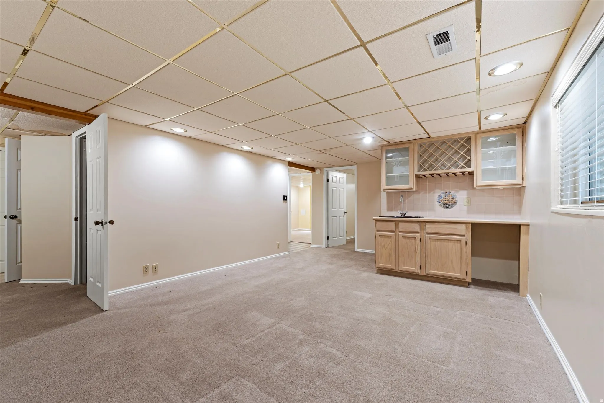 Expansive basement with built-in cabinetry, sink, and bar area, perfect for entertaining or multi-functional use.