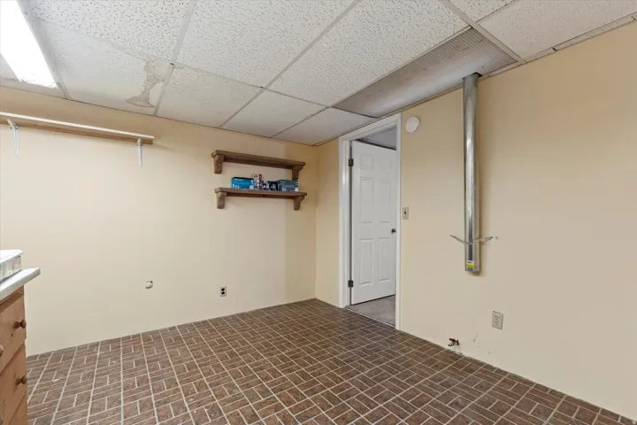 Dedicated laundry and utility space with built-in workbench, cabinetry, and pegboard wall for organized storage and projects. Durable flooring, overhead lighting, and additional shelving provide a functional area for laundry, hobbies, or workspace needs.