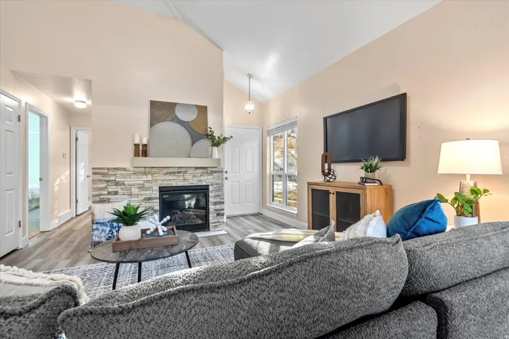 Cozy living space featuring a stone-accented fireplace as the focal point, complemented by modern flooring and a functional layout.