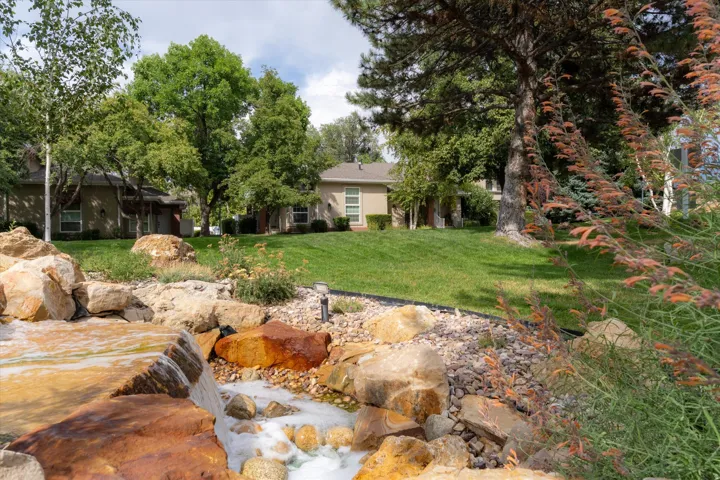 Scenic landscaped water feature with natural stone accents and flowing waterfall, creating a tranquil and inviting outdoor environment.